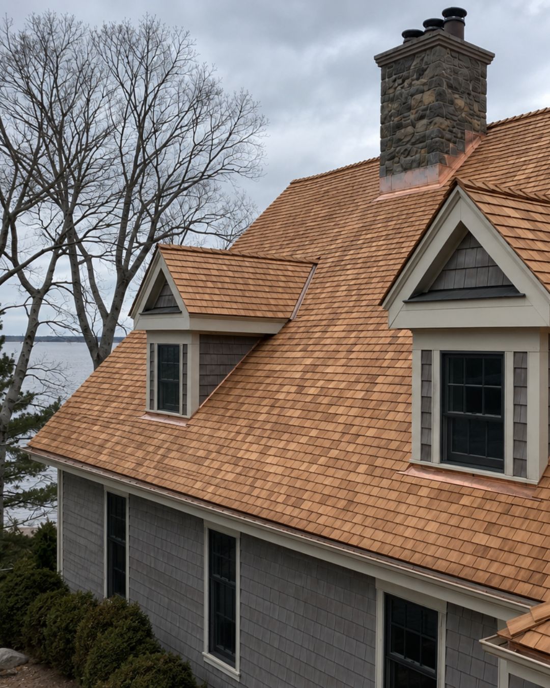 Completed cedar shingle roof with dormers, chimney, and detailed residential rooflines.
