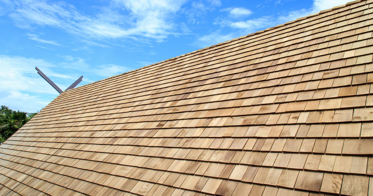 Rows of natural cedar shingles carefully aligned across a residential roof.