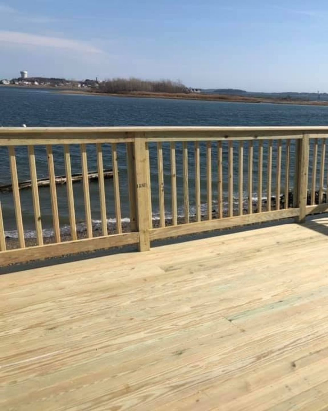 Completed outdoor wood deck and railing built for a residential property near the Massachusetts coast.