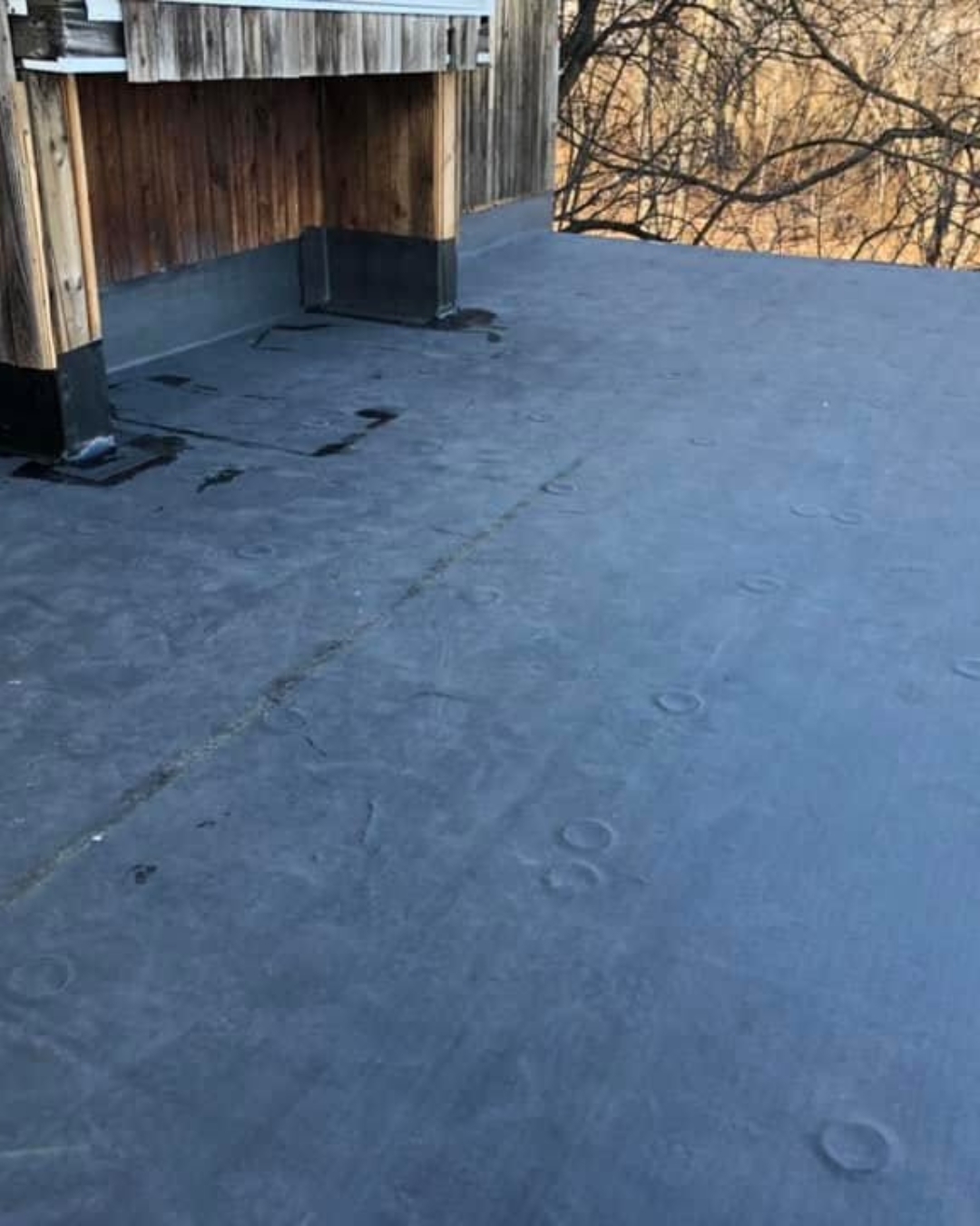 Professional inspection of a flat roof before EPDM rubber roofing installation in Massachusetts.