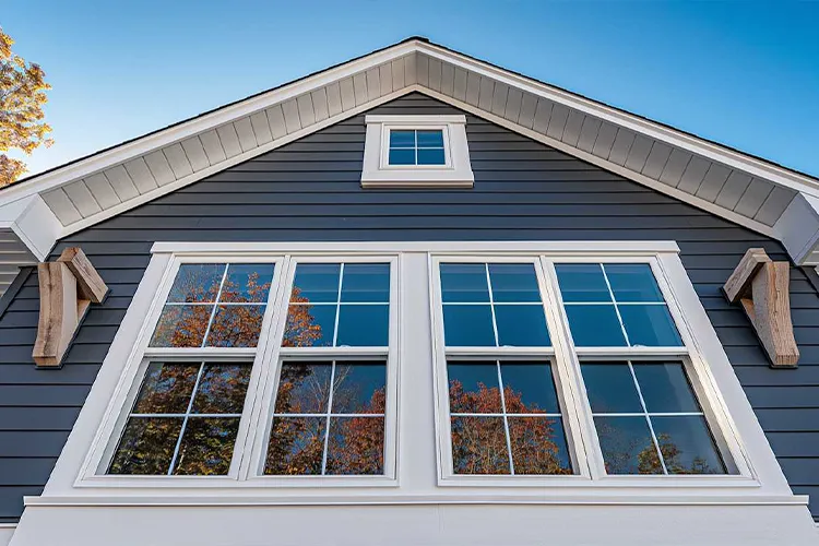 New England home exterior featuring dark siding and newly installed white replacement windows